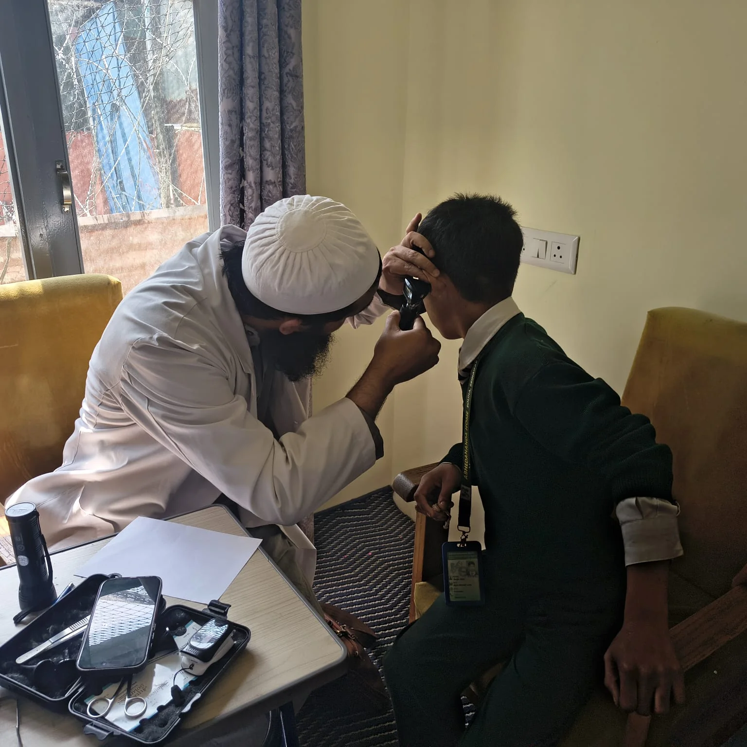 A clinician examines a student's ear during the screening at Abhedananda Home